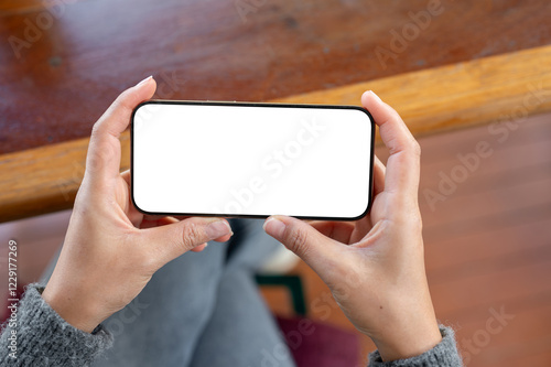 A top view of a woman holds a smartphone in a horizontal positive as she watching videos.