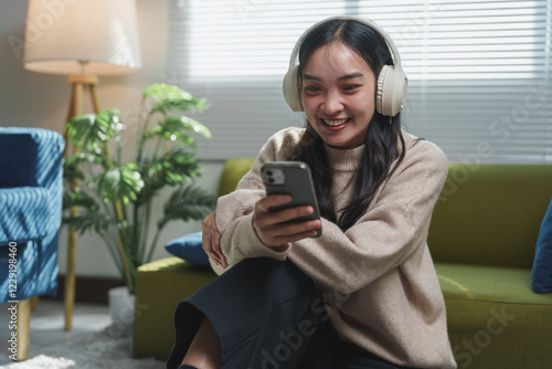 Photography Smiling young woman with headphones enjoying music while looking at her smartphone