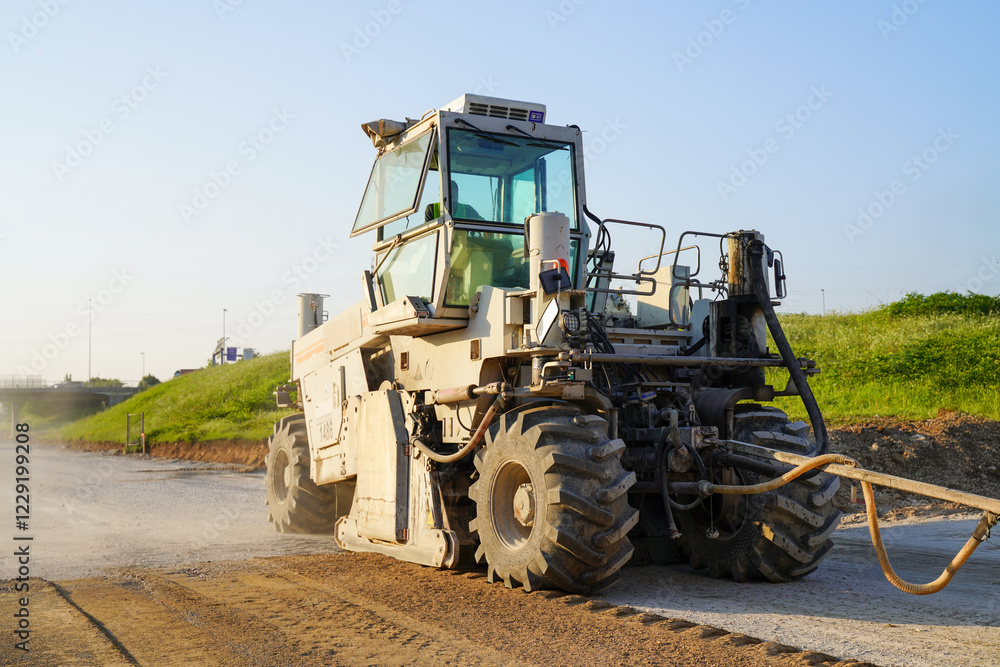 Heavy-duty asphalt recycler on a highway construction site, processing old pavement to create a stable foundation for a new asphalt layer Heavy-duty asphalt recycler on a highway construction site, processing old pavement to create a stable foundation for a new asphalt layer