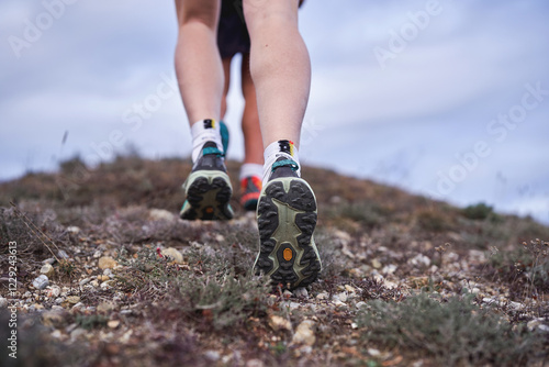 Obraz na plátně Close-up of hikers’ feet walking uphill on a rugged trail with hiking shoes