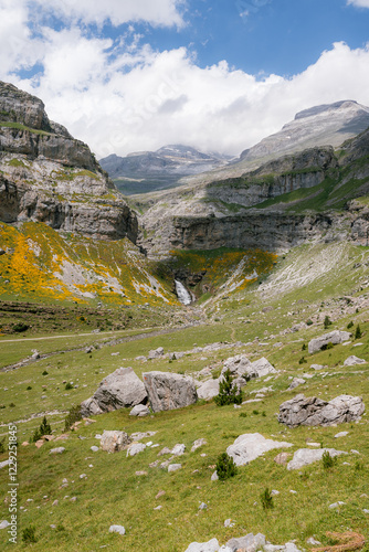 A breathtaking view of a lush mountain valley with a waterfall in Ordesa y Monte Perdido National Park, Spain. A perfect destination for trekking, hiking, mountaineering, and summer outdoor adventures