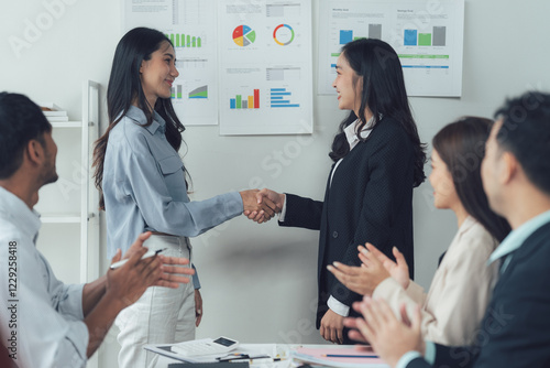 Business Deal: Two professionals shake hands, sealing a deal, while their team applauds in the background, creating a positive and collaborative atmosphere.   photo