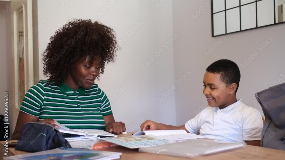 Woman assisting boy with schoolwork at the table Woman assisting boy with schoolwork at the table
