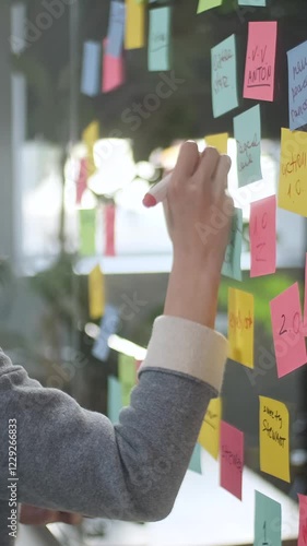 Asian Business Woman Write Tasks Creative Ideas On Sticky Notes On Glass Board, Female Corporate Leader Planning Project On Post It Sticky Notes Organize Work On Stickers