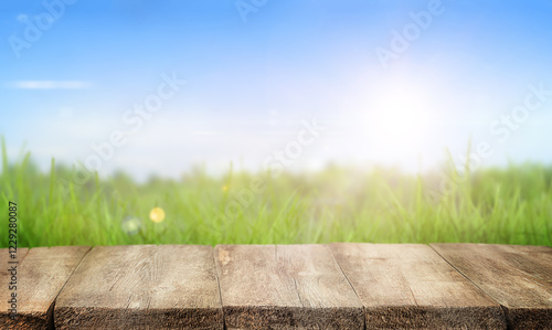 Fototapeta Naklejka Na Ścianę i Meble -  wooden empty table in foreground and grass field with blue sky in background