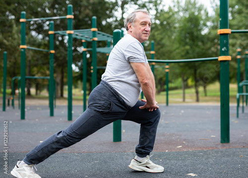 Konstfotografi Elderly man doing gymnastics on an outdoor sports ground