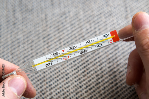 Obraz na płótnie Measuring body temperature with a classic thermometer, health and medicine.
w salonie