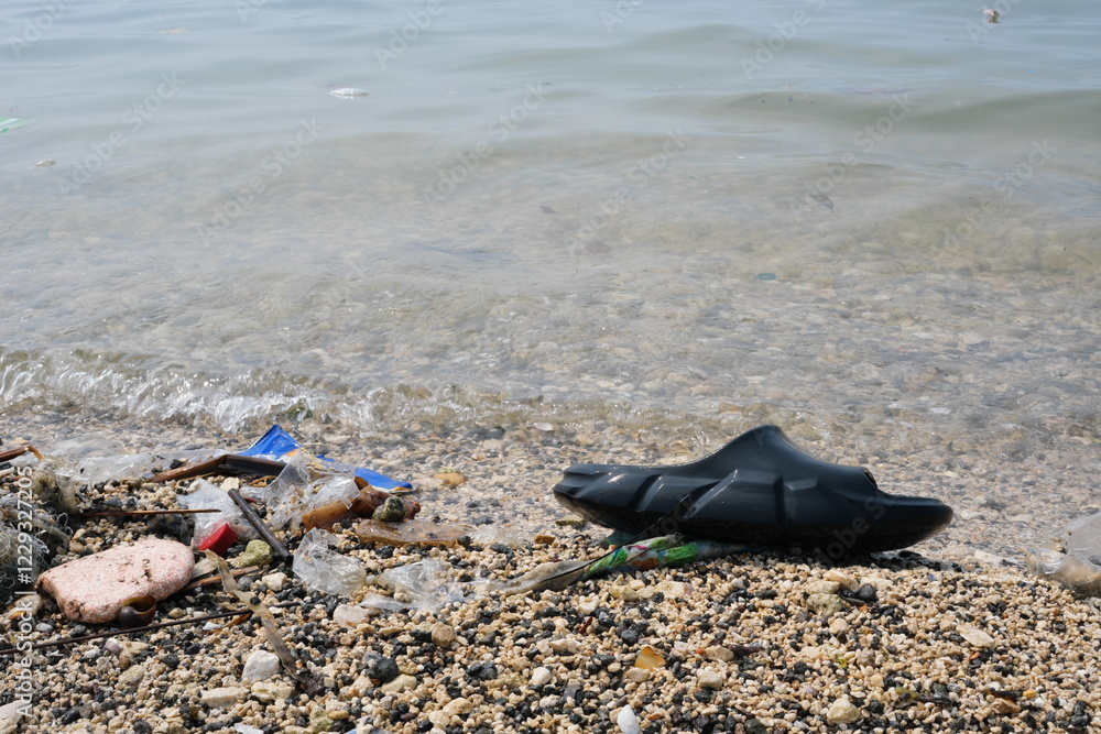 Garbage trash rubbish waste being washed to the shoreline by sea waves.
