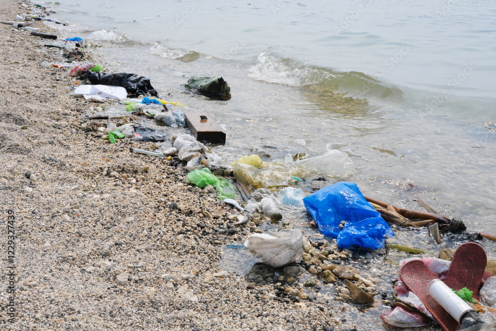 Garbage trash rubbish waste being washed to the shoreline by sea waves.