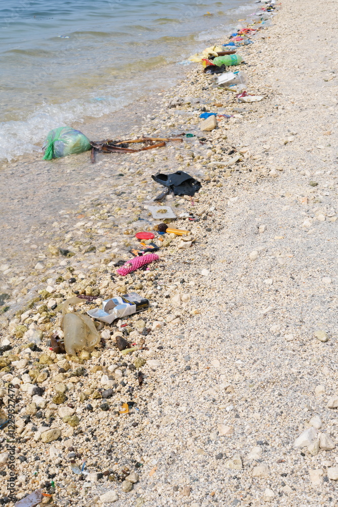 Garbage trash rubbish waste being washed to the shoreline by sea waves.