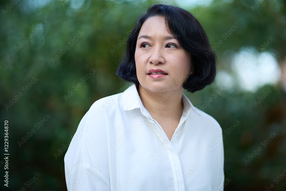 Portrait of smiling middle aged Asian business women in natural background Portrait of smiling middle aged Asian business women in natural background
