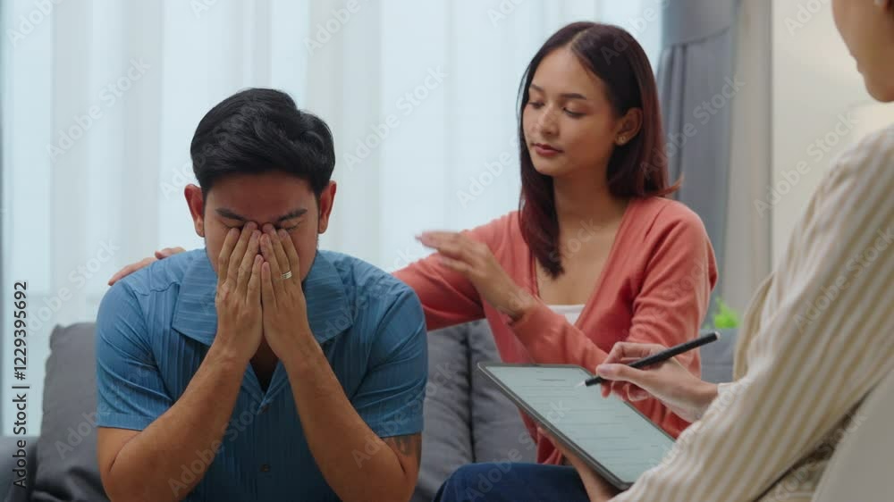 distressed asian man covers his face with his hands during a couple's therapy session distressed asian man covers his face with his hands during a couple's therapy session