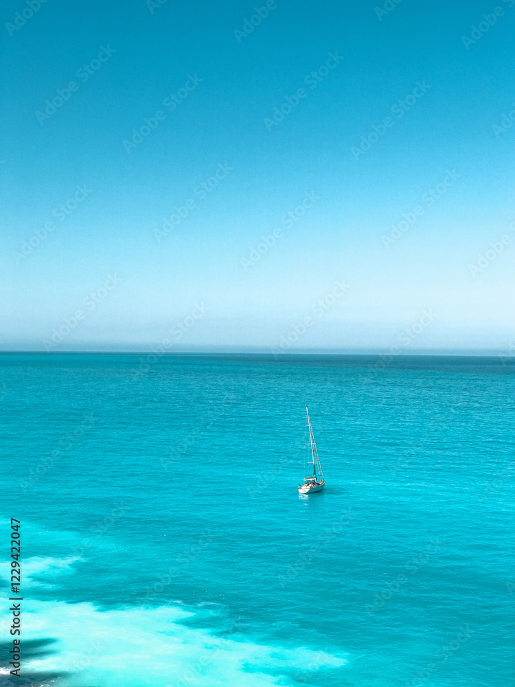 Fototapeta premium A lone boat floating on calm waters near a rugged coastline. Concept of escape, solitude, and the boundless beauty of nature