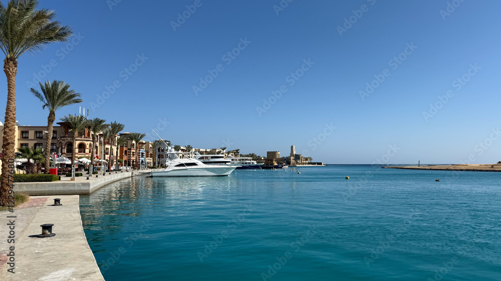Obraz premium Scenic Marina View with Yachts and Waterfront Buildings Under Clear Blue Sky