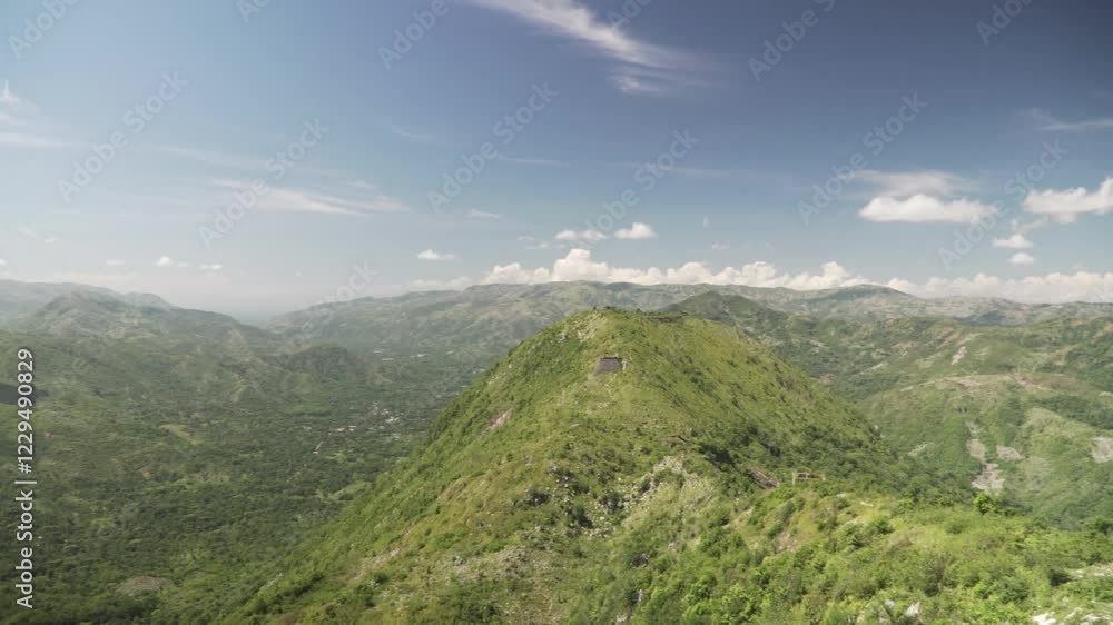 Haiti's lush green mountains feature an old fortress under a blue sky with white clouds. Haiti's lush green mountains feature an old fortress under a blue sky with white clouds.