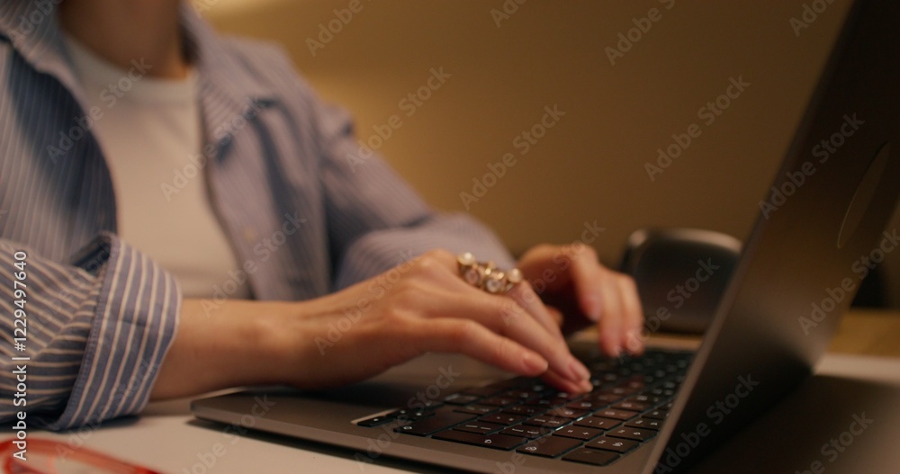A woman typing on a laptop keyboard sitting at a table indoors, close-up of her hand, unrecognizable person A woman typing on a laptop keyboard sitting at a table indoors, close-up of her hand, unrecognizable person