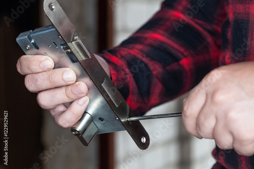 Wallpaper Mural A male locksmith installs a new door lock on a metal door. Torontodigital.ca