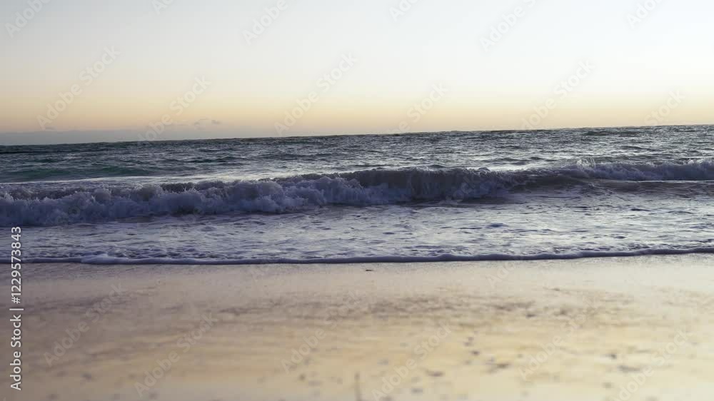 Beautiful ocean waves crash into a sandy beach during sunrise in tropical Punta Cana, Dominican Republic. Beautiful ocean waves crash into a sandy beach during sunrise in tropical Punta Cana, Dominican Republic.