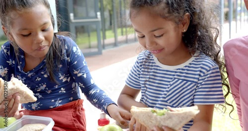 In school, children eating lunch together, enjoying sandwiches and apples