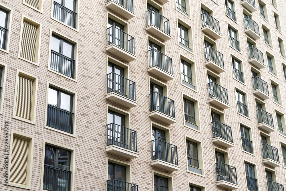 Modern residential building with repeating balconies, metal railings, and brick facade. Urban housing concept on a bright exterior Modern residential building with repeating balconies, metal railings, and brick facade. Urban housing concept on a bright exterior