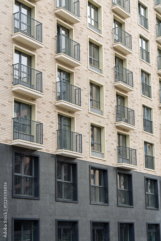 Contemporary building facade featuring small balconies and a mix of brick and dark panels. Urban housing concept on a clear day Contemporary building facade featuring small balconies and a mix of brick and dark panels. Urban housing concept on a clear day