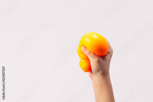 Hand squeeze orange stress ball on green background. Positive thinking concept