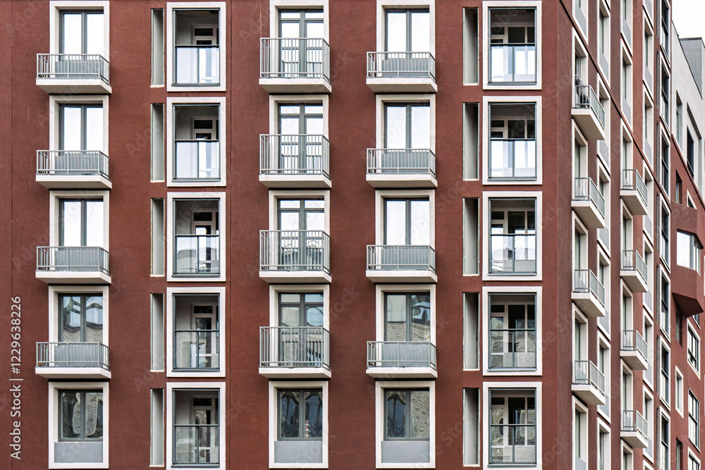 Red facade of a modern building with symmetrical balconies windows and metal railings, urban architectural style, contemporary housing concept Red facade of a modern building with symmetrical balconies windows and metal railings, urban architectural style, contemporary housing concept