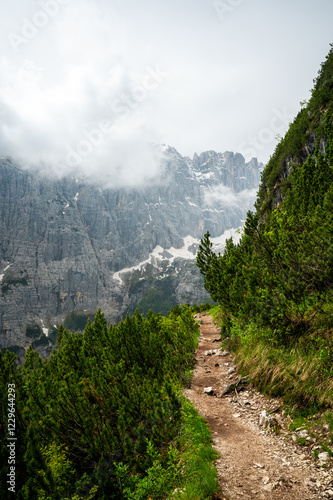 Obraz na płótnie Mountain trail in the Dolomites (Dolomiti, Dolomiten), Italy, leading to Lago Sorapis. The path winds along rocky slopes with stunning views of valleys, forests, and peaks w salonie