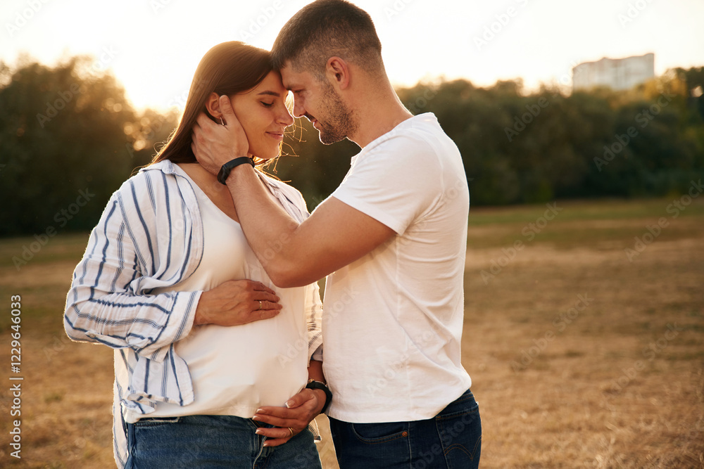 Pregnant woman is waiting for a child. Beautiful couple is in love, standing on the field together Pregnant woman is waiting for a child. Beautiful couple is in love, standing on the field together