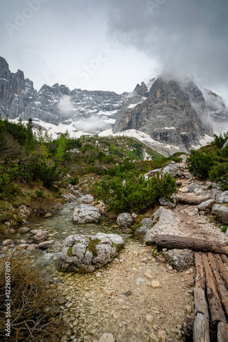 Obraz na płótnie Rocky hiking trail near Lago Sorapis in the Dolomites (Dolomiti, Dolomiten), Italy. The path runs alongside a small mountain stream, with massive boulders and peaks in the background w salonie