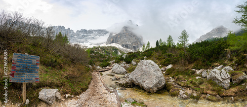Obraz na płótnie Rocky hiking trail near Lago Sorapis in the Dolomites (Dolomiti, Dolomiten), Italy. The path runs alongside a small mountain stream, with massive boulders and peaks in the background w salonie