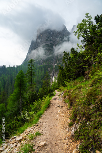 Obraz na płótnie Mountain trail in the Dolomites (Dolomiti, Dolomiten), Italy, leading to Lago Sorapis. The path winds along rocky slopes with stunning views of valleys, forests, and peaks w salonie