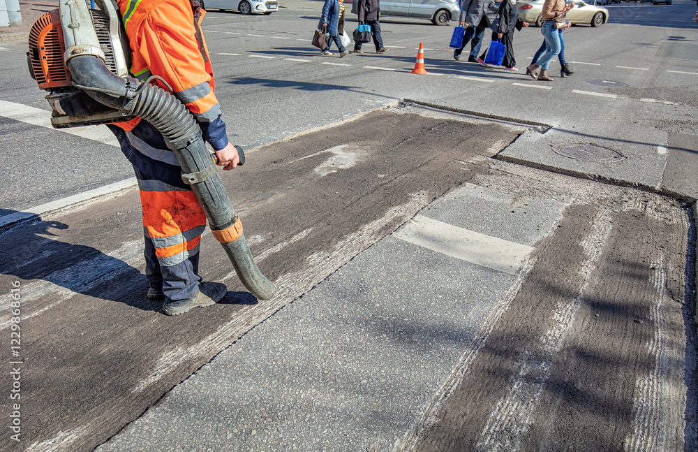 Street maintenance crew working on pavement repair during a bright sunny day