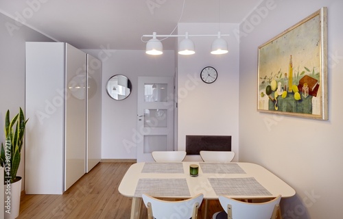 Salon w nowoczesnym apartamencie z beżową sofą, białym stołem z krzesłami photo