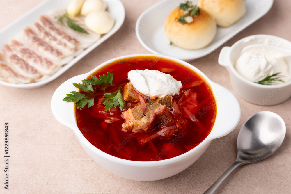 Borsch with pampushki (buns), sour cream, lard and garlic. Traditional Russian and Ukrainian soup with meat, beets, cabbage and potatoes. Close-up, selective focus. Borsch with pampushki (buns), sour cream, lard and garlic. Traditional Russian and Ukrainian soup with meat, beets, cabbage and potatoes. Close-up, selective focus.