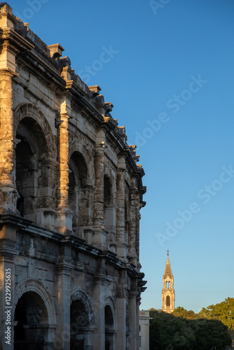 Ancient Roman amphitheatre and Church of Sainte Perpetue in Nimes at sunset, Occitanie region of southern France