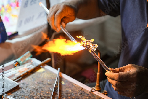 Creating glass art with hot torch and glassblowing pipe. The process of glass making, Glassblower shaping the red melted glass, A glass blower melting glass