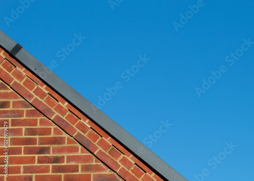 brown brick wall under the roof against the background of bright blue sky