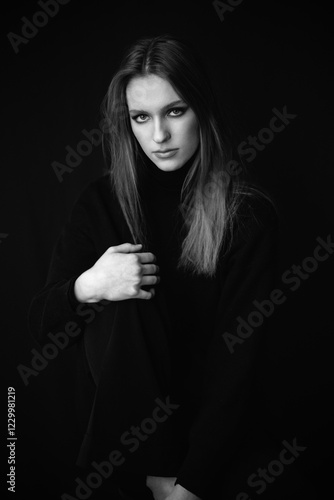 A striking black and white portrait of a woman with deep shadows and high contrast. Her intense gaze and sculpted features create a bold, dramatic, and timeless aesthetic
