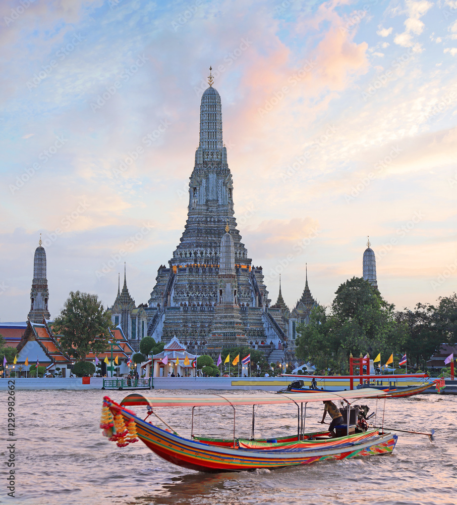 Fototapeta premium Wat Arun Temple at sunset with traditional boat on the river on the foreground, Bangkok, Thailand