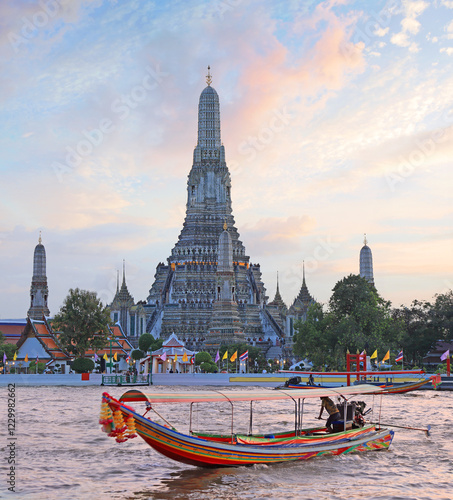 Wat Arun Temple at sunset with traditional boat on the river on the foreground, Bangkok, Thailand