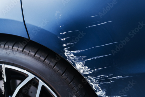 Transport accident. Deep scratch on blue car near wheel.