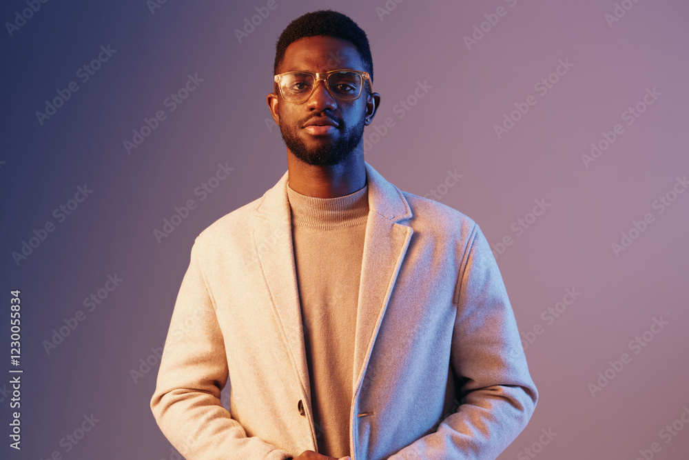 Obraz premium Stylish young African man wearing glasses and a light coat, standing against a colorful purple background, exuding confidence and modern fashion