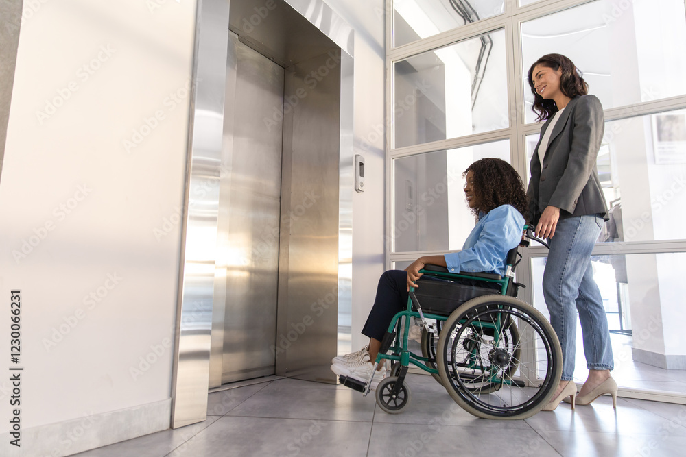 Disabled woman in wheelchair presses waiting the elevator with female colleague in the office Disabled woman in wheelchair presses waiting the elevator with female colleague in the office