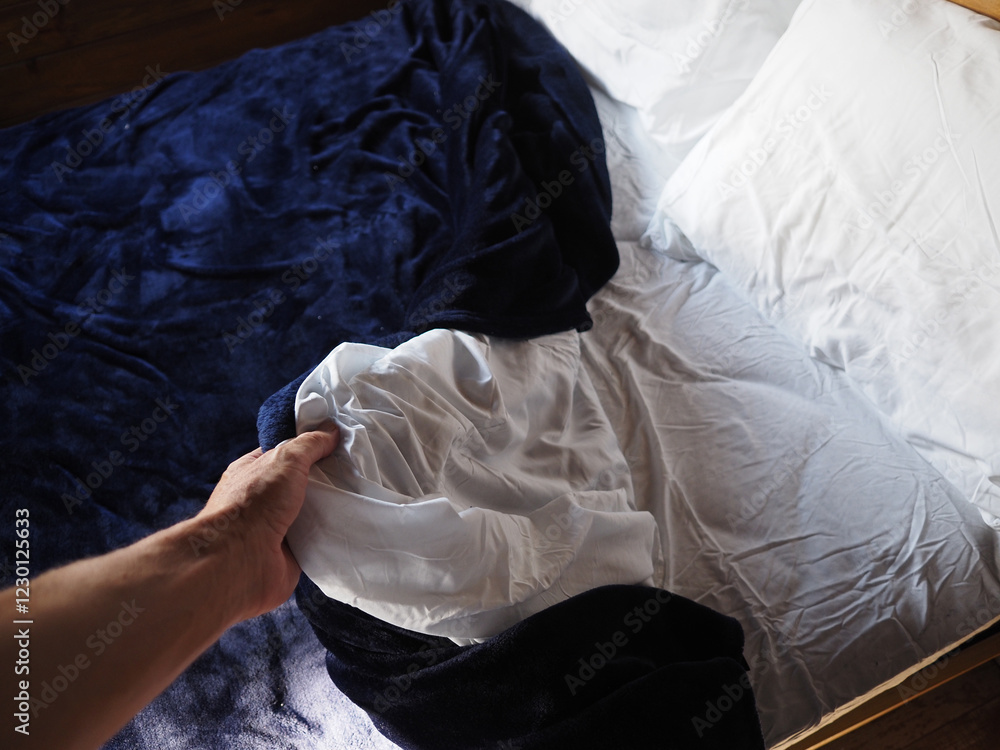 POV of cozy bed with soft white sheets and a plush navy blanket in a warm bedroom during the daytime. Take a nap. POV of cozy bed with soft white sheets and a plush navy blanket in a warm bedroom during the daytime. Take a nap.