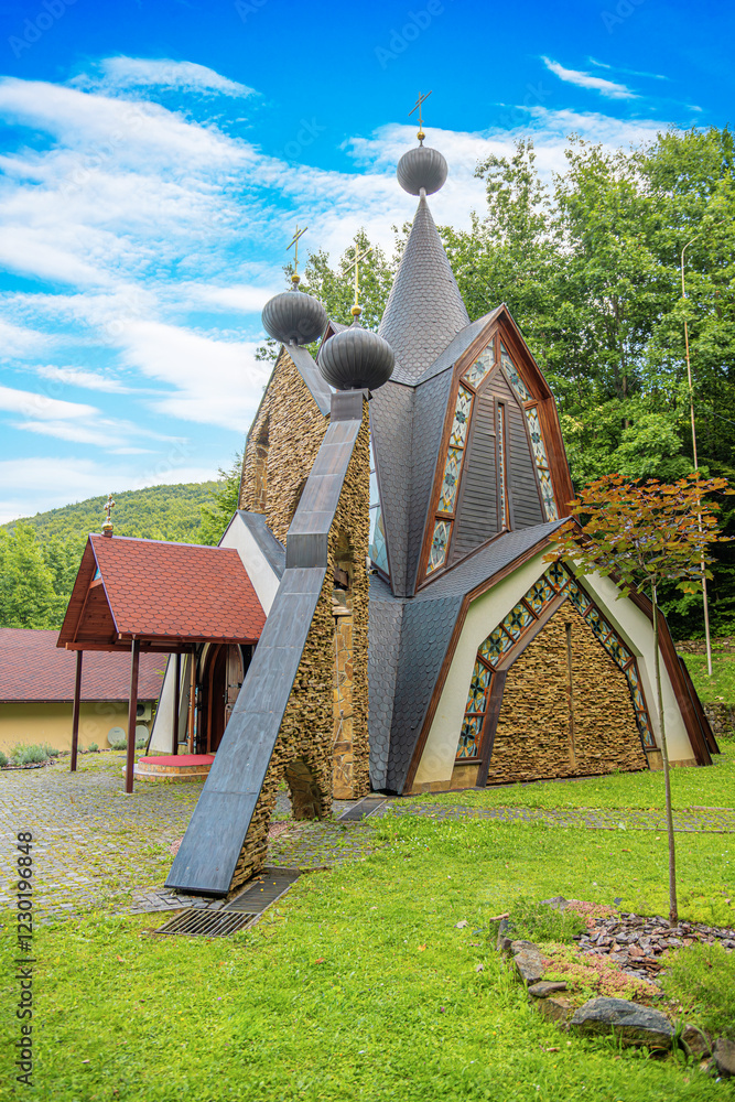 Orthodox church with a combination of wooden and stone elements, featuring onion-shaped domes and beautiful stained-glass windows.