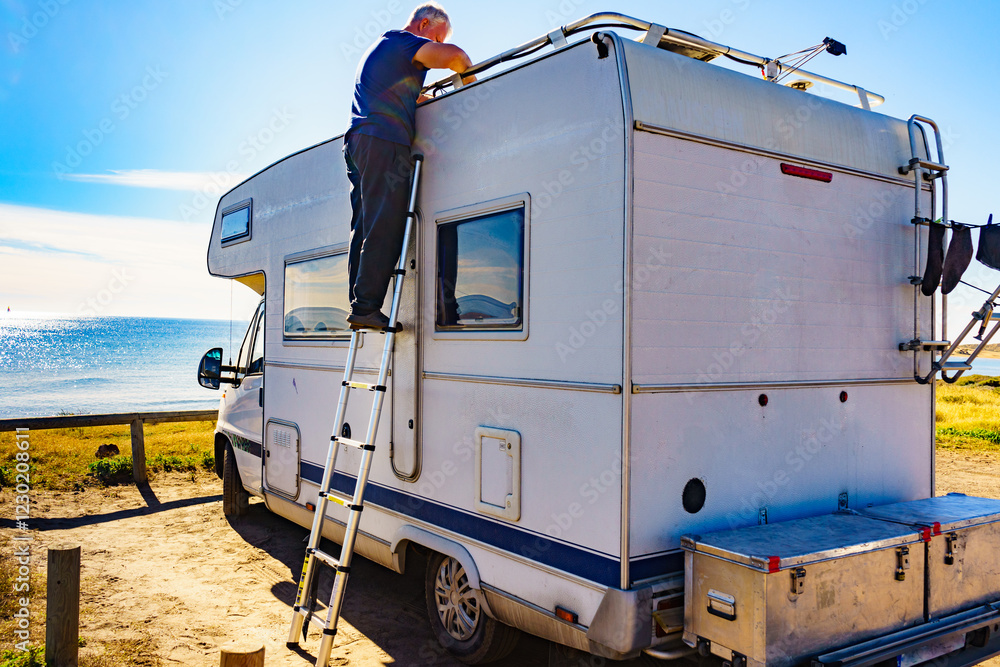 Man on ladder at caravan. Repair motor home.
