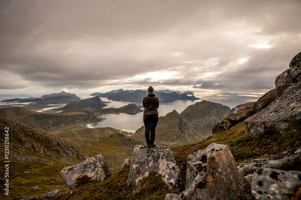 Frau bei Wanderung mit atemberaubender Aussicht auf Berge und Fjorde der Lofoten
