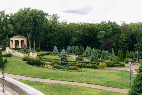 Well-maintained landscaping design featuring a gazebo, manicured lawns, a variety of trees, and winding pathways creating an inviting and luxurious outdoor space