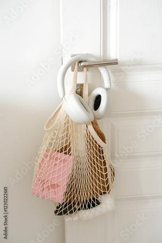 Woman accessoties in the netting bag - passport, headphons, hat, sunglasses hanging on door handle in bedroom. photo